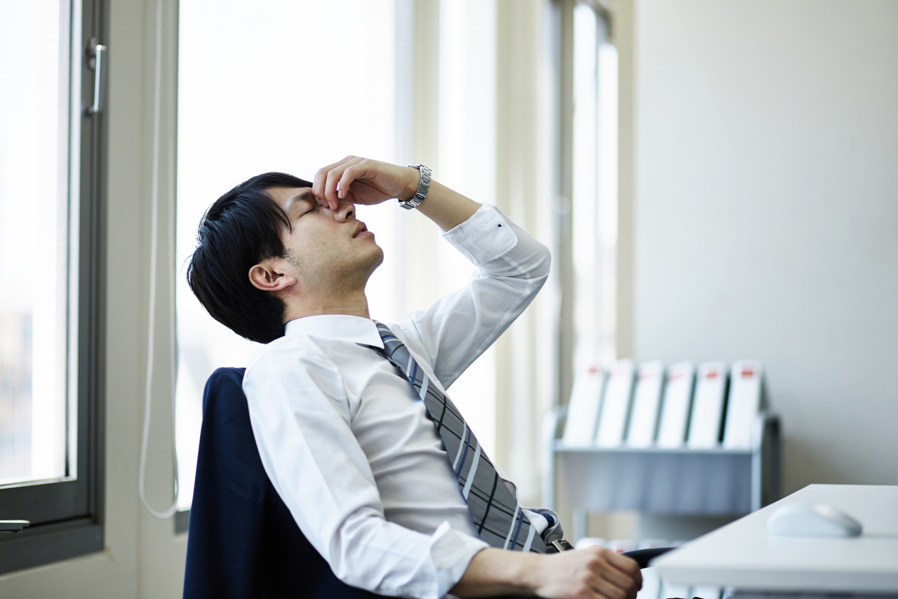 眼精疲労のために目を休める男性