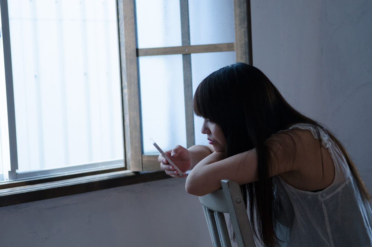 暗い部屋でスマホを見る女性